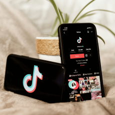Two smartphones showing the TikTok app with logo and profile screen, symbolizing TikTok’s growth and influence