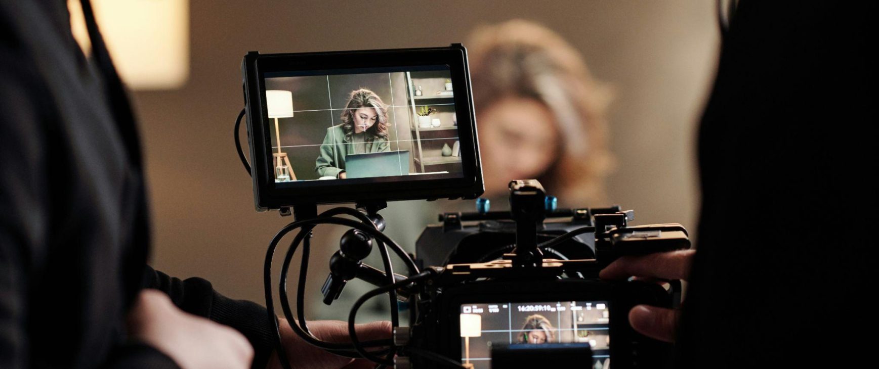 Video crew viewing a woman working on her laptop through a camera monitor as they produce long-form content that will be reused across channels