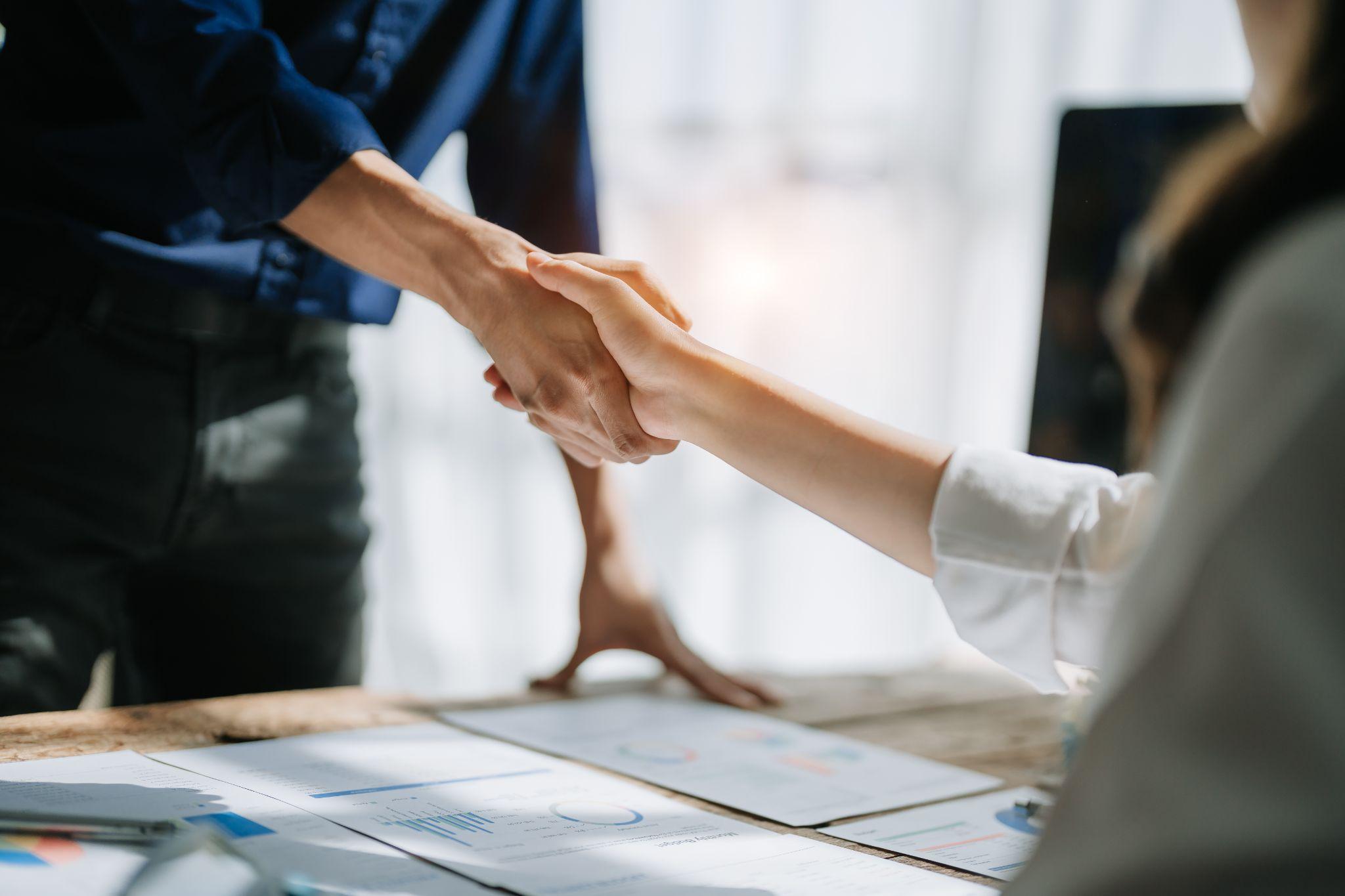 Two people shaking hands over a table