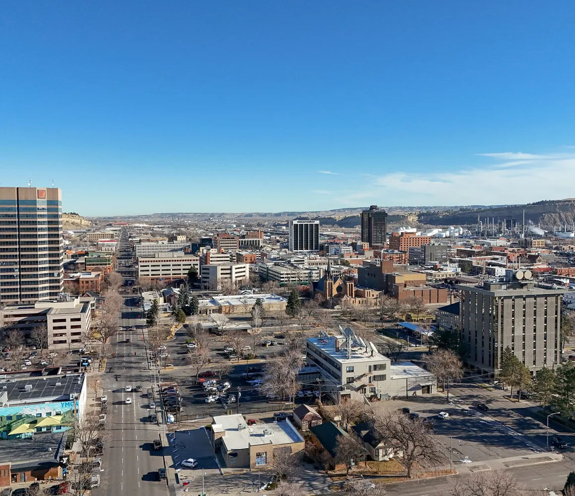 Aerial view across downtown Billings toward the sandstone rimrocks, bare trees and clear blue winter sky