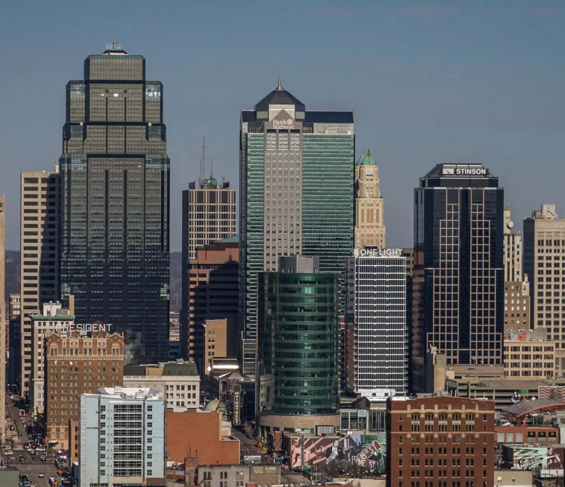 Downtown Kansas City's clustered high-rises, including a dark crowned tower, under a clear winter sky