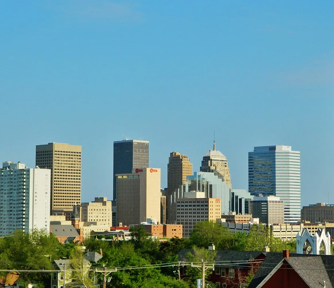 Oklahoma City's downtown towers under clear blue sky, a tall pointed glass tower at the right