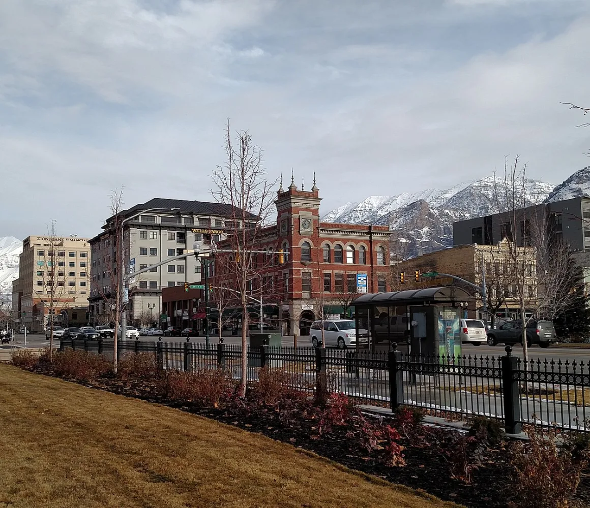 Snow-capped mountains rise behind downtown Provo's red-brick clock tower and bare winter trees