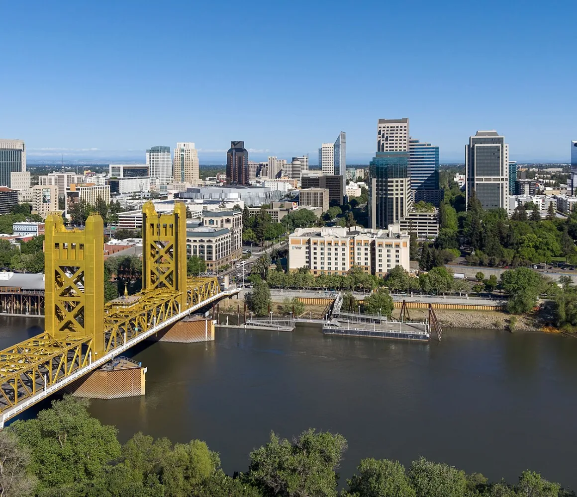Sacramento's golden Tower Bridge crossing the river with the downtown skyline behind under clear sky